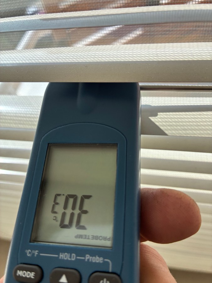 Měření teploty okenního skla po aplikaci fólie, přibližně 30 °C